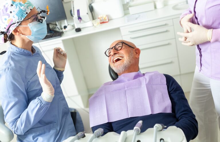 Photo of a woman sitting in a dental chair, attentively listening to a dentist who is pointing to a set of after-care instructions post tooth extraction. No text on the image.